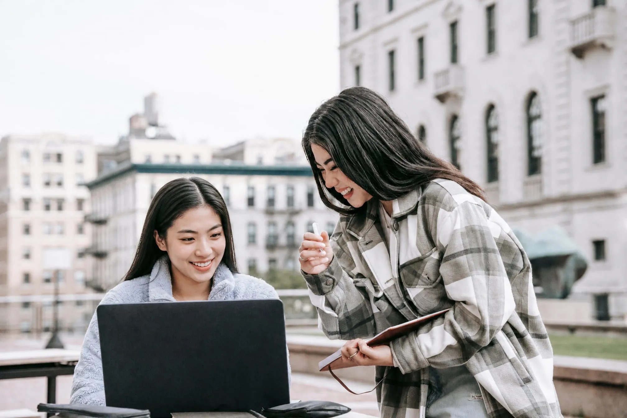 Two students reviewing work on a laptop on campus