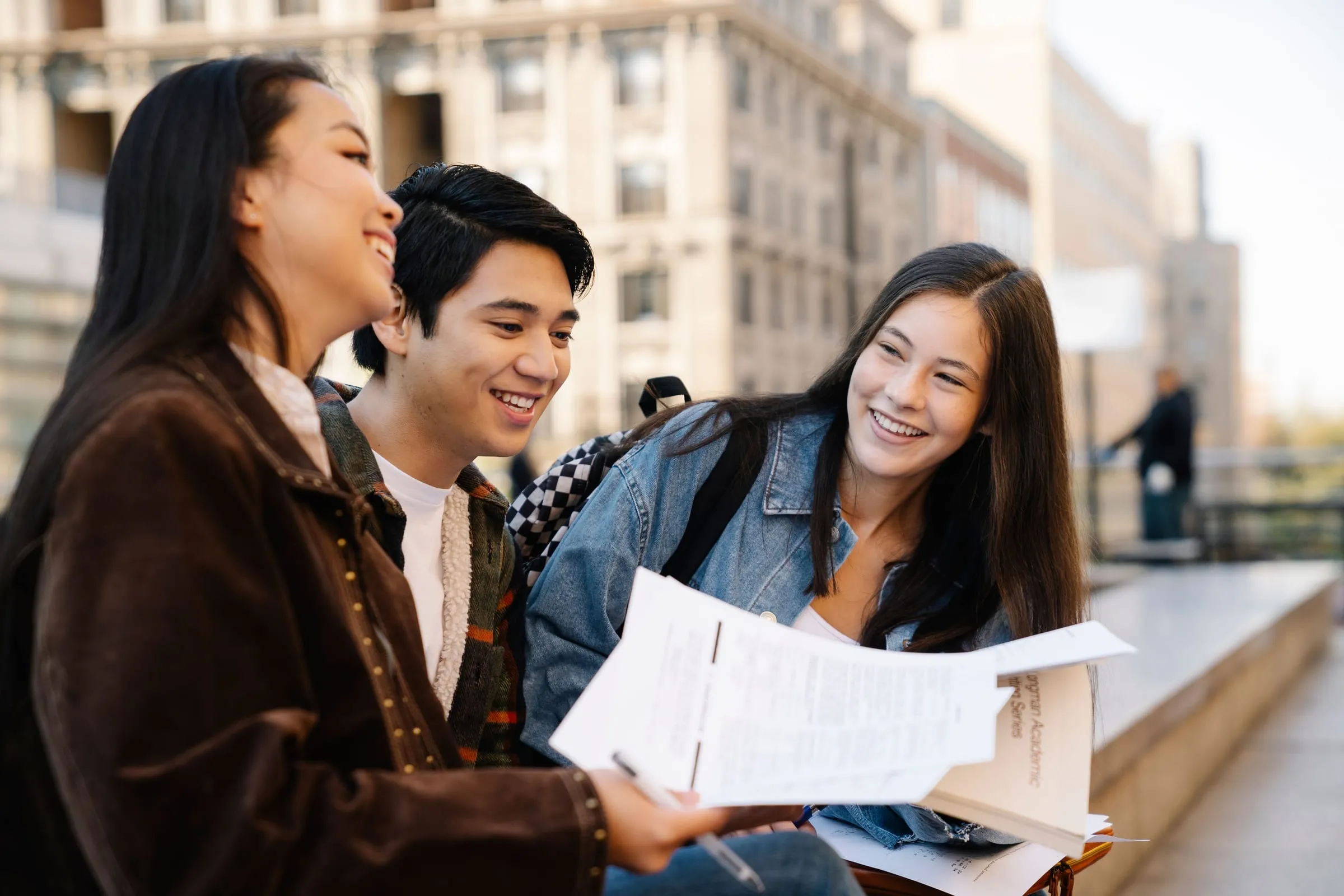 Three students reviewing notes together on campus
