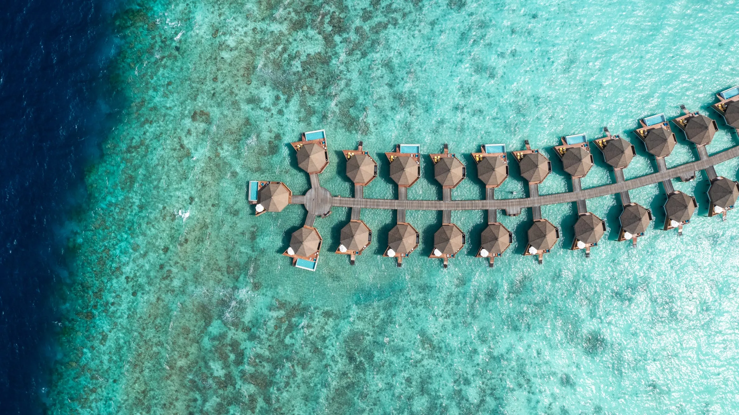Overwater villas from above on a turquoise reef
