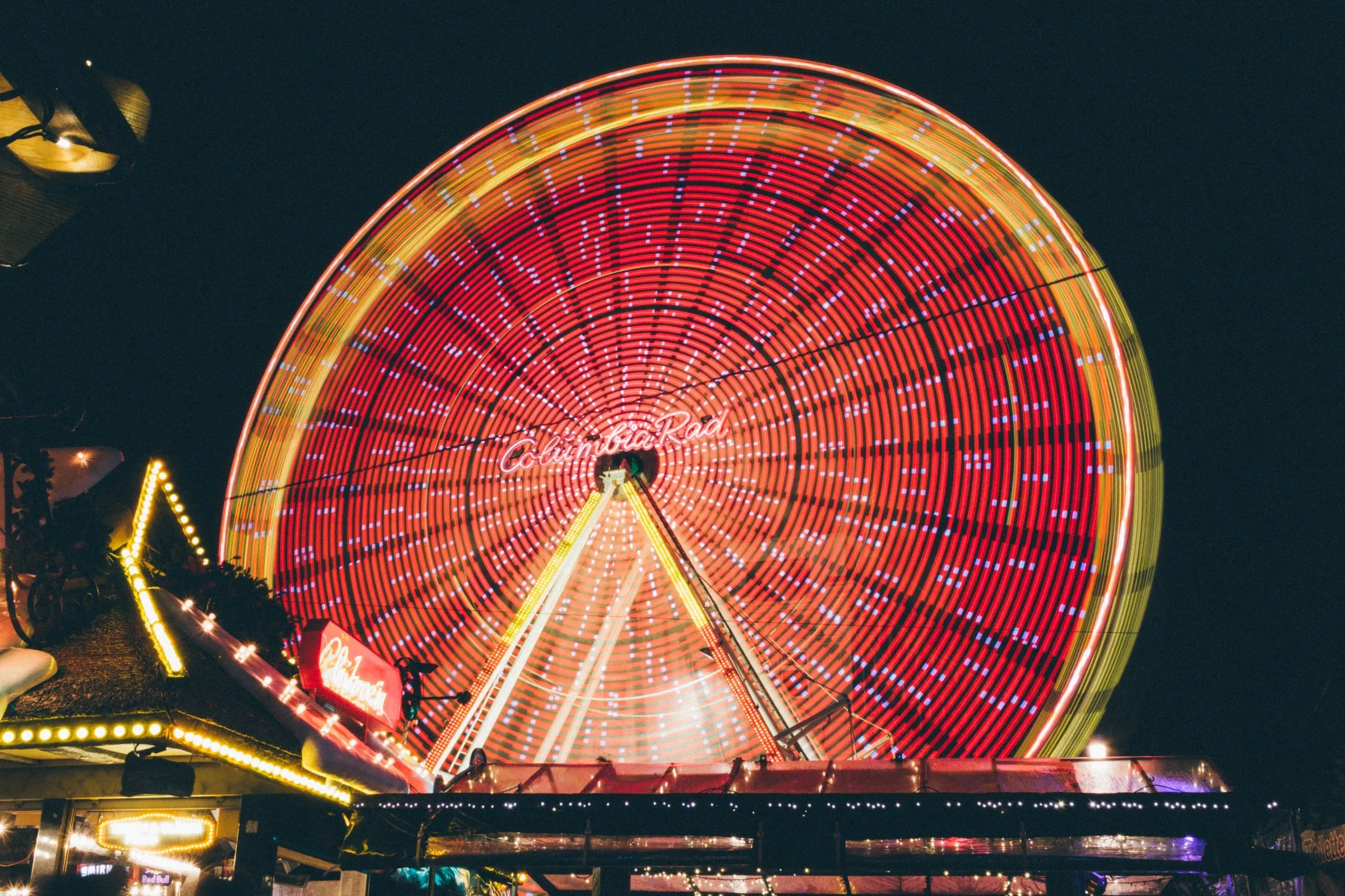 Illuminated Ferris wheel spinning at night in an amusement park